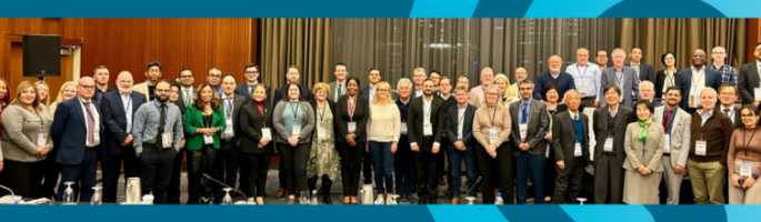 Groupe de plus de 80 personnes du monde entier en tenue de travail.