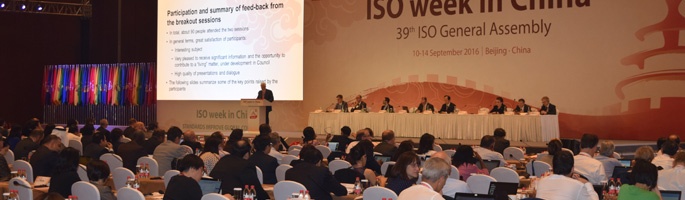 John Walter speaking in front of large audience at ISO General Assembly